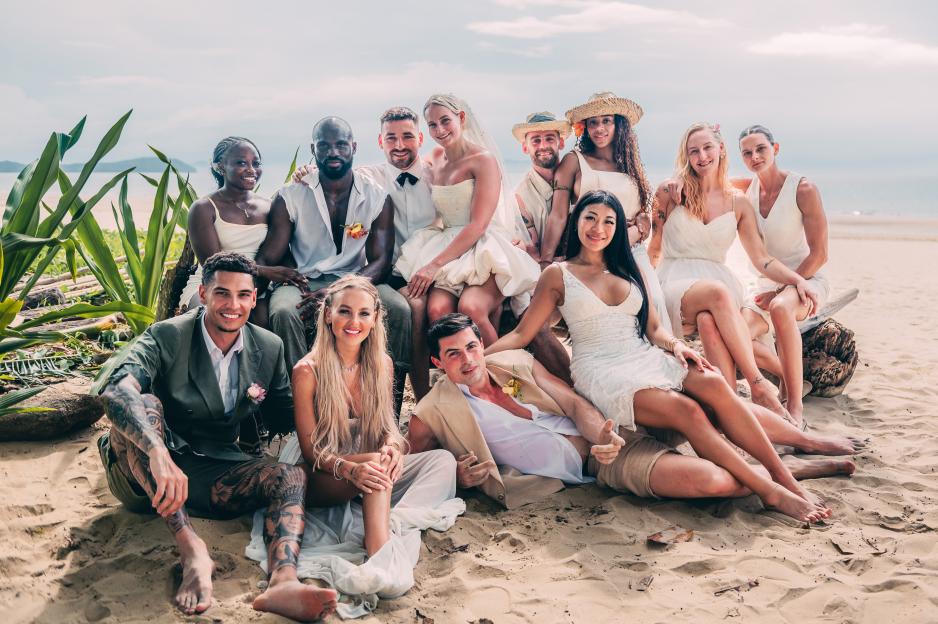 Group photo of couples on a beach.