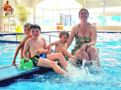 Woman and three boys at a poolside.
