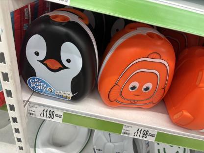 Portable potties on a store shelf; one is penguin-themed, the other is clownfish-themed.