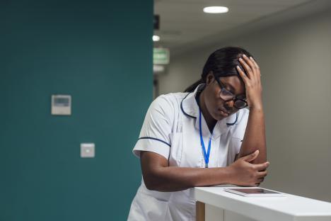 A student nurse looking concerned while using a tablet.
