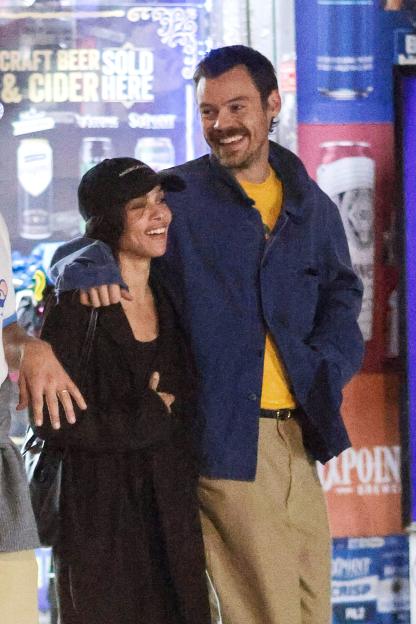 Harry Styles and Zoe Kravitz smiling and walking arm-in-arm.