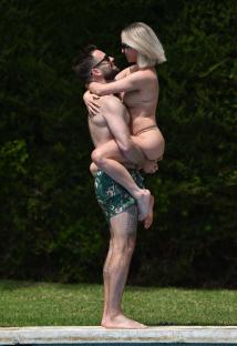 Man lifting woman by the pool.