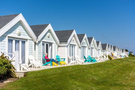 Row of seaside cottages with people relaxing outside.