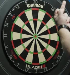 A hand gesturing near a dartboard.