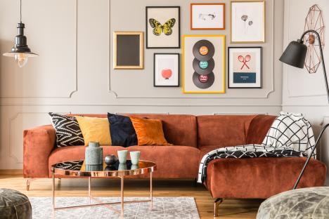 Eclectic living room with orange velvet sectional sofa and gallery wall.