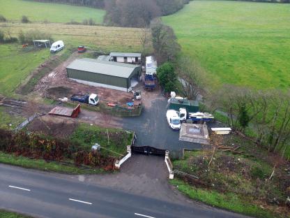Aerial view of a property with several vehicles and construction materials.