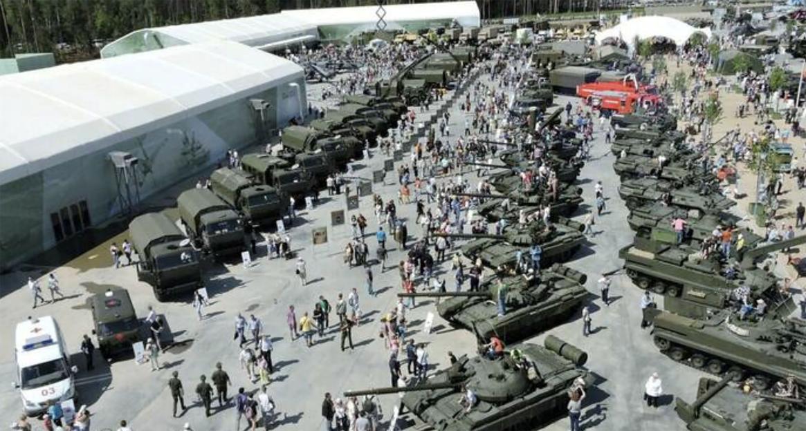 Patriot Park near Moscow, an exhibition of military vehicles and tanks with large white tents and a crowd of people.