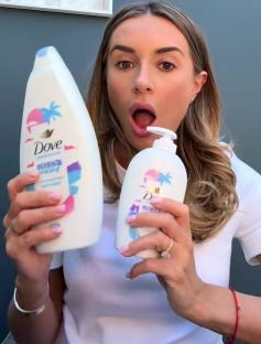 Woman holding two Dove body wash bottles.