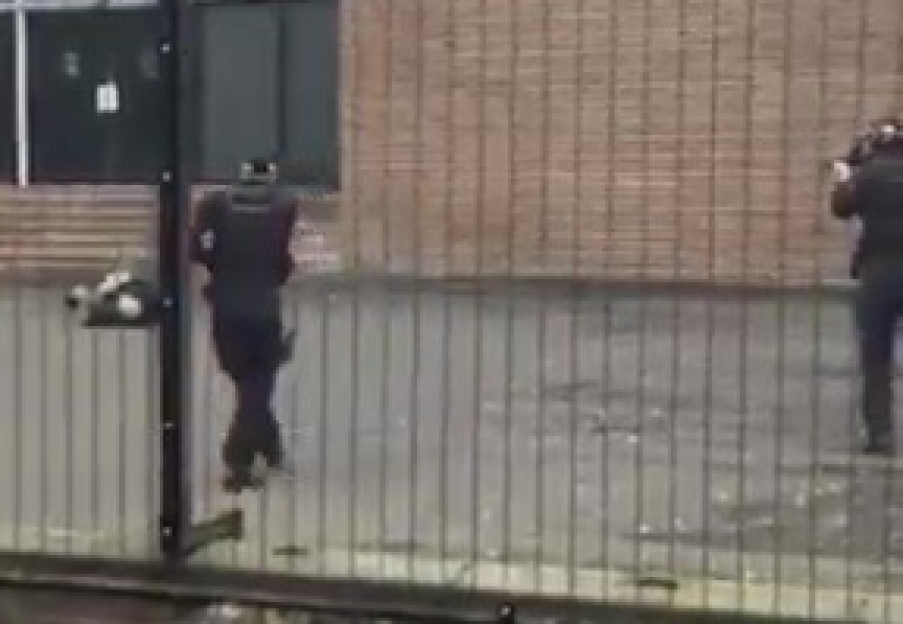 Two police officers behind a metal fence.