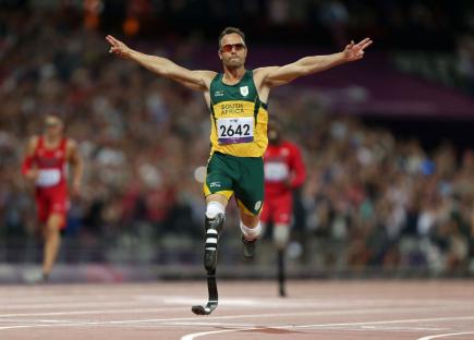 Paralympic athlete in mid-jump, arms outstretched.