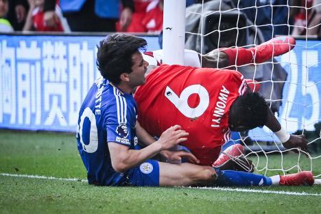 Two soccer players colliding near the goal post.