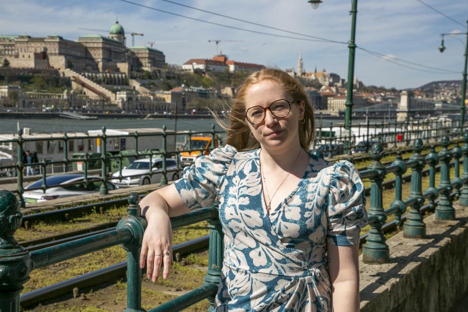 A woman in Budapest, leaning on a railing with Buda Castle in the background.