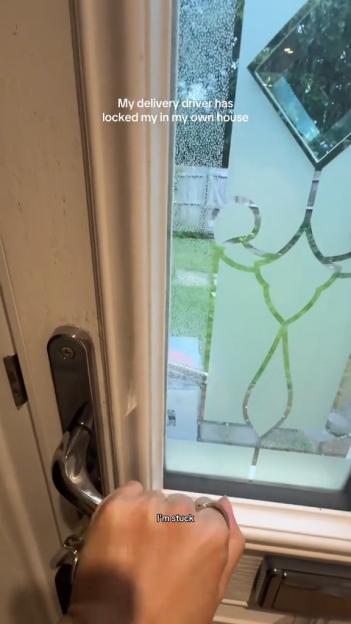 A hand trying to open a door that is blocked by a large package visible through the frosted glass.