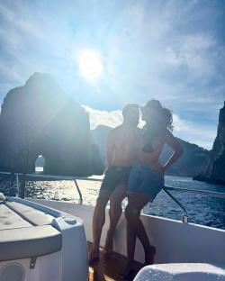 Couple embracing on a boat, with dramatic rock formations in the background.