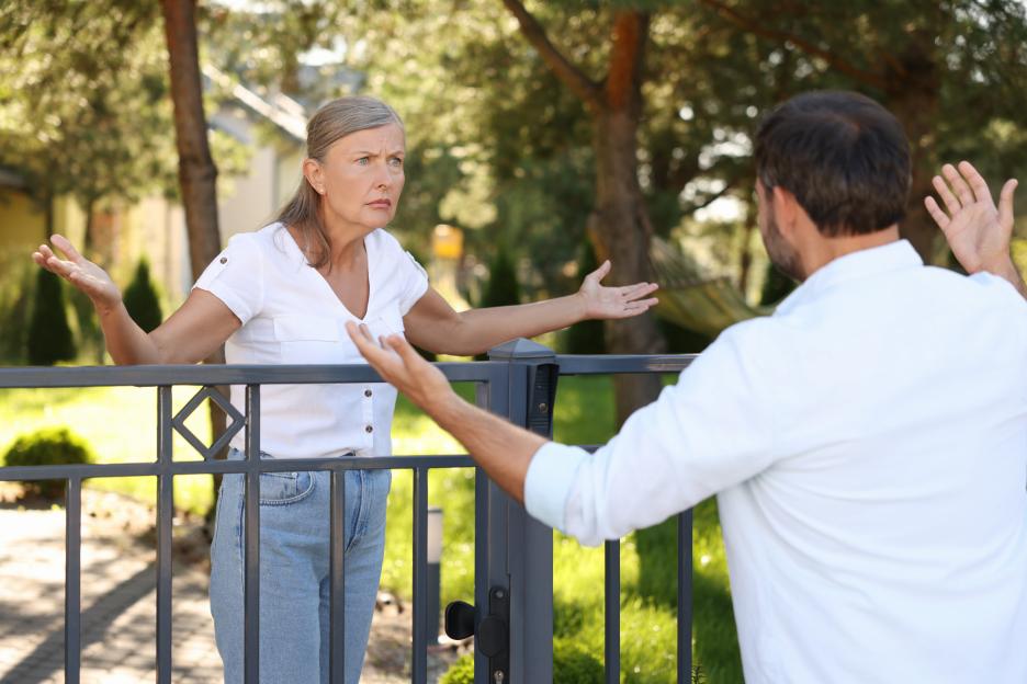 Two neighbors arguing at a fence.
