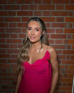Woman in pink dress against brick wall.