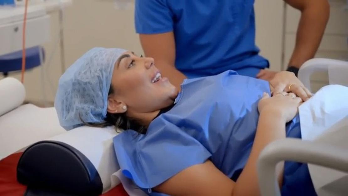 Woman in a medical gown lying on an examination table during a medical procedure.