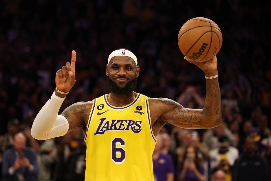 LeBron James, in a Lakers uniform, holding a basketball and smiling after breaking the NBA's all-time scoring record.