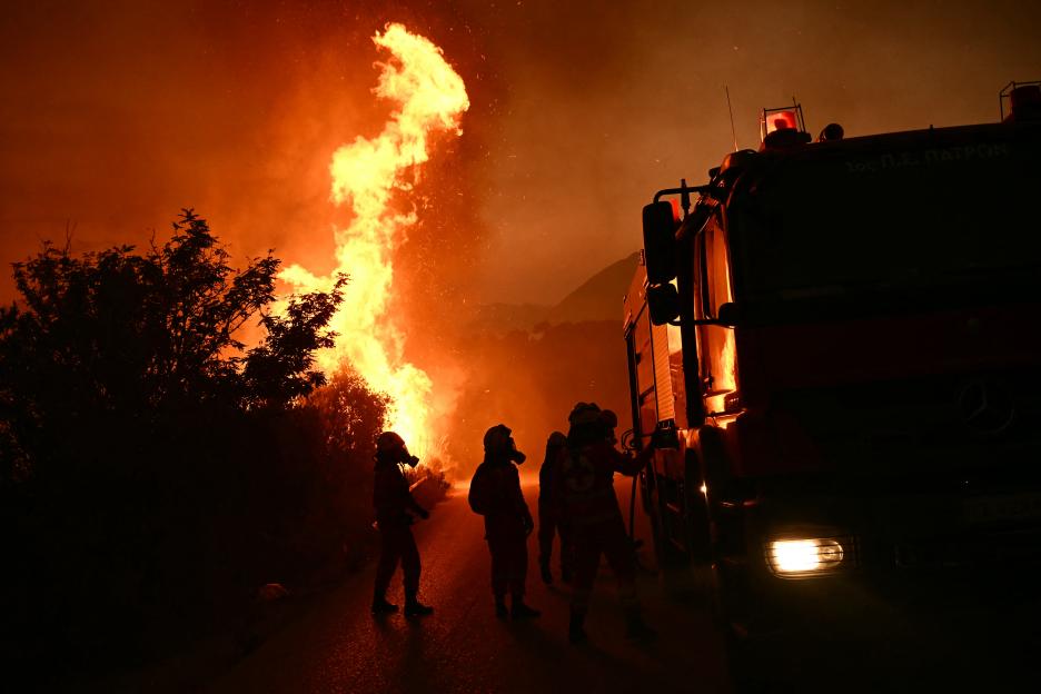 Firefighters battling a wildfire at night.