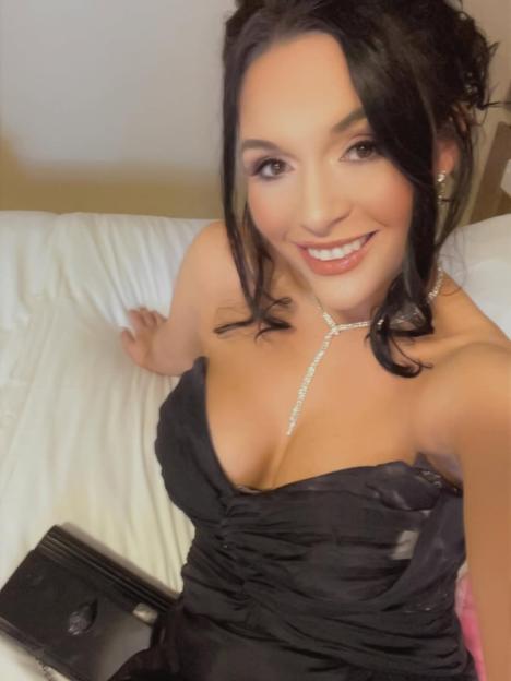 Woman in black dress smiling at camera.