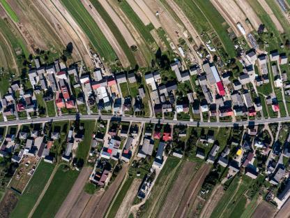 Aerial view of Suloszowa, Poland, a long village with a single street surrounded by agricultural fields.