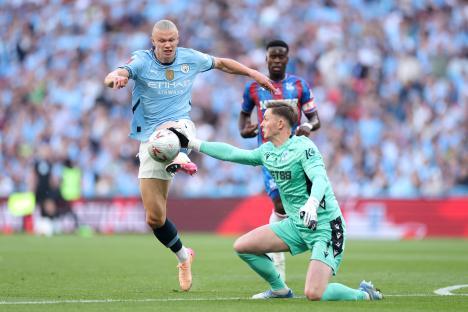 Dean Henderson of Crystal Palace clearing the ball from Erling Haaland of Manchester City.