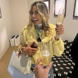 Woman holding champagne flutes and shopping bags.