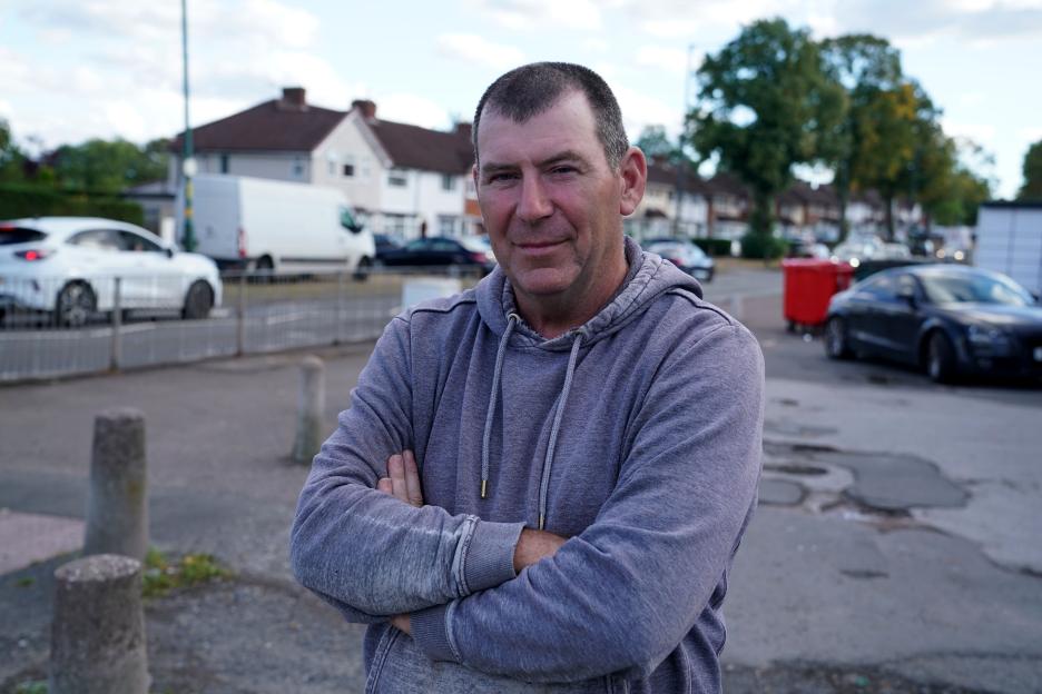 Portrait of Adrian Tracy, 57, standing with arms crossed.