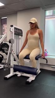 Pregnant woman using leg extension machine at the gym.