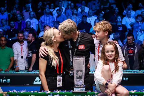 Neil Robertson of Australia kisses his wife and embraces his children after winning a snooker competition.