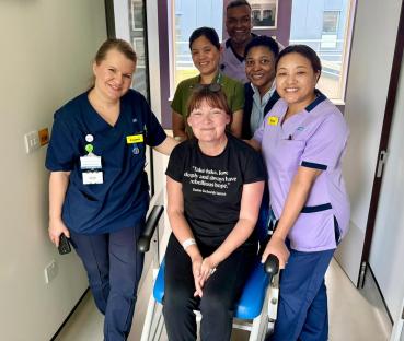 A woman in a wheelchair surrounded by hospital staff.