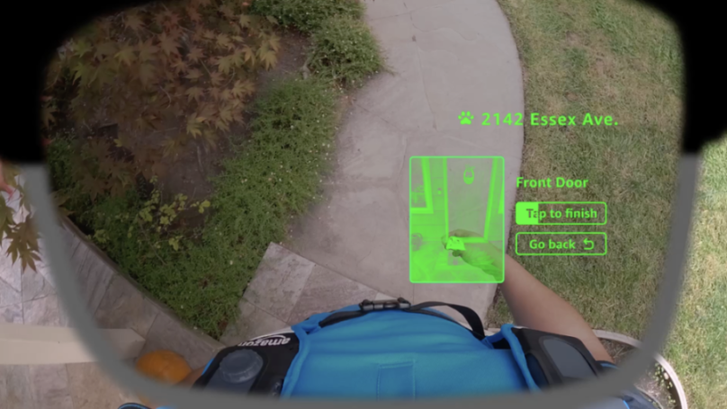First-person view of smart glasses displaying "2142 Essex Ave." and "Tap to finish" over a package being delivered.