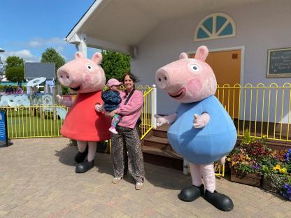 A woman and child pose with Peppa Pig characters at Paultons Park.
