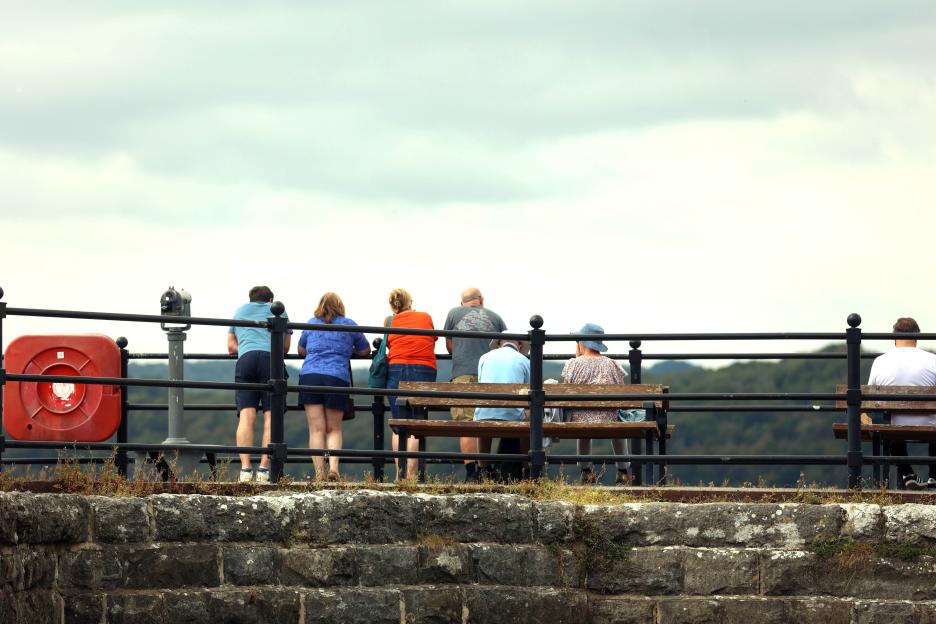 People looking out at a view from a seaside wall.