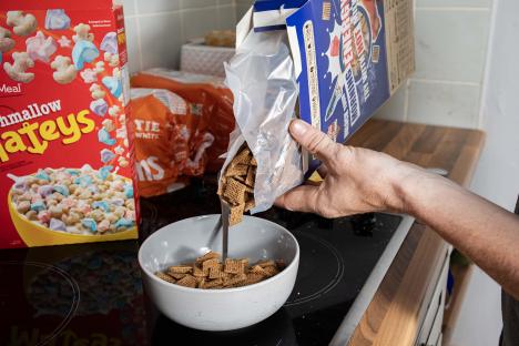 A person pouring cereal into a bowl.