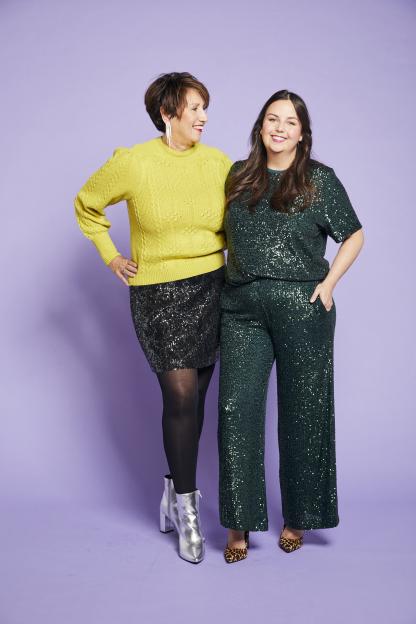 Abby McHale and her mother model Christmas party wear, with Abby in a green sequin top and pants, and her mother in a yellow sweater and black sequin skirt.