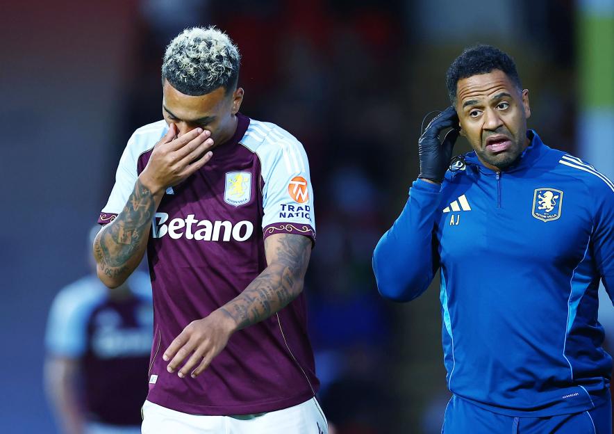 Injured Aston Villa player being attended to by a trainer.