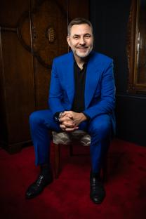 David Walliams seated, smiling, in a blue suit.