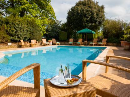 Two drinks and snacks on a tray by a pool.