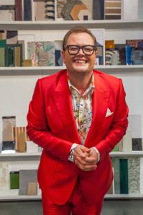 Alan Carr in a red suit, smiling.