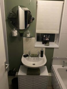 Bathroom makeover with green walls, white sink and vanity, and round mirror.