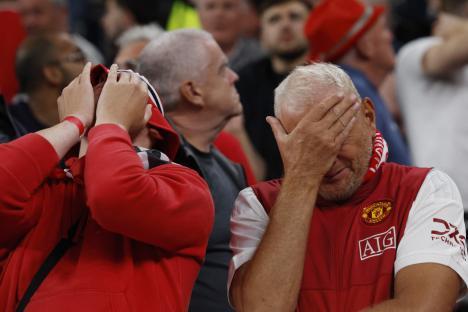 Dejected Manchester United fans at a soccer match.