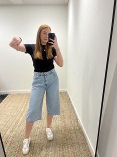Woman giving a thumbs down while wearing denim shorts.