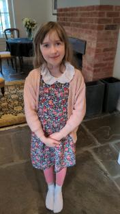 Girl in floral dress and pink cardigan.