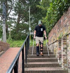 Man on crutches climbing stairs.