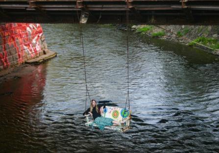 Woman relaxing on a painted swing hanging over a river.