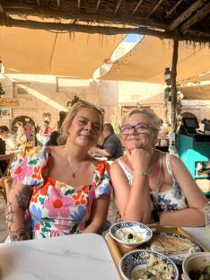 Two women sitting at a table outdoors, sharing a meal.