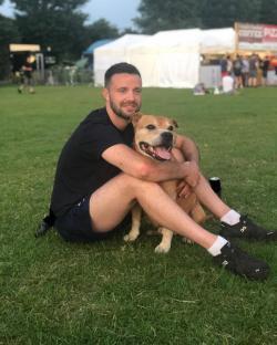 Man sitting on the grass hugging his dog.