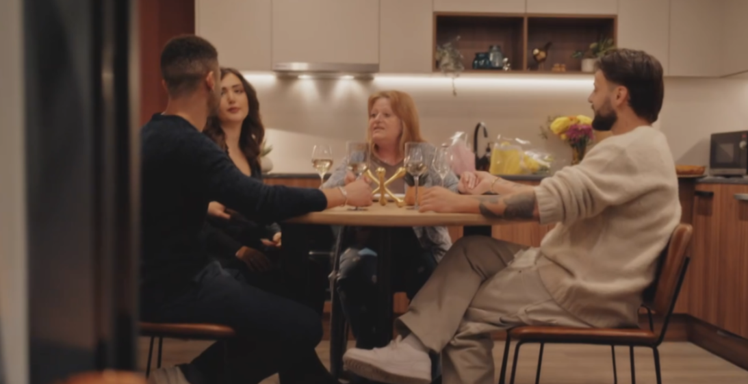 Four people sitting around a kitchen table, talking.