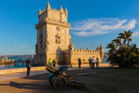 The Belém Tower in Lisbon, Portugal, with tourists and a cannon in the foreground.